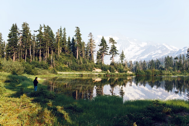 See umgeben von Bäumen, schneebedeckte Berge im Hintergrund